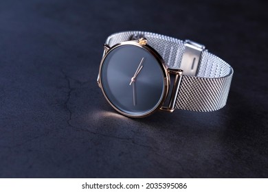 Black wrist watch for women with metal strap top view on gray background. Focus on the those of clock.