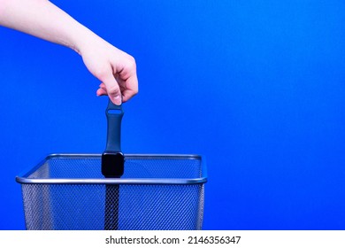 A Black Wristwatch Is Thrown Into The Trash On A Blue Background