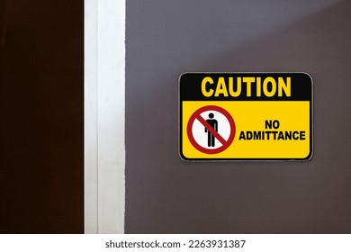 Black and yellow caution sign on the side of an open door stating "Caution, No admittance".