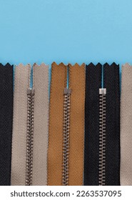 Black, yellow, grey zippers on a blue background. Top view. Copy space.