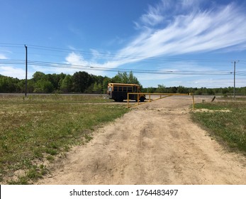 A Black And Yellow Short Bus At The Edge Of A Dirt Road With Power Lines In The Background.