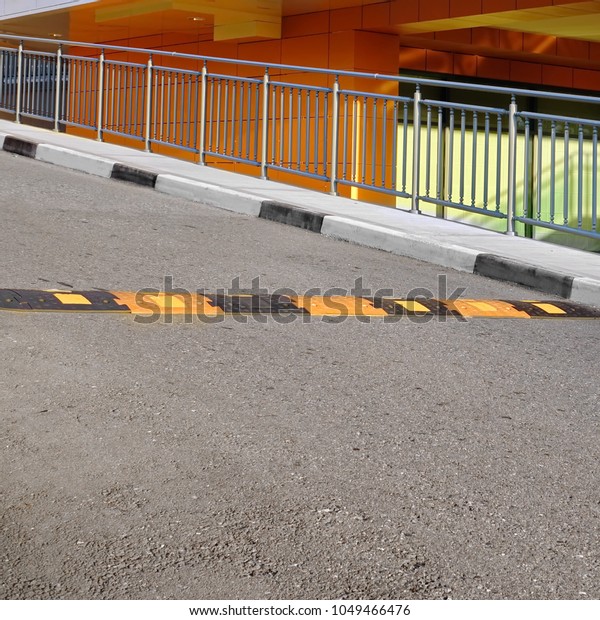 Black And Yellow Small Speed Bump On Asphalt\
Road, An Obstacle On The Road, Drive Up To Garage, Road Bend Near\
The Building