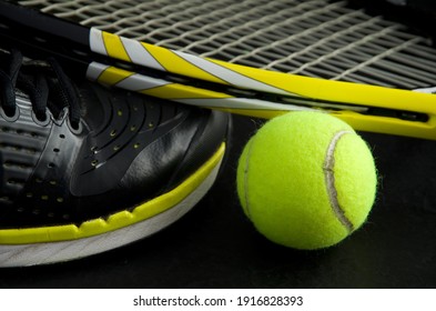 Black And Yellow Tennis Shoe With Tennis Ball And Racquet In Background Horizontal