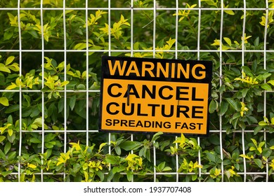 Black and yellow warning sign on a fence stating "Warning, cancel culture spreading fast".