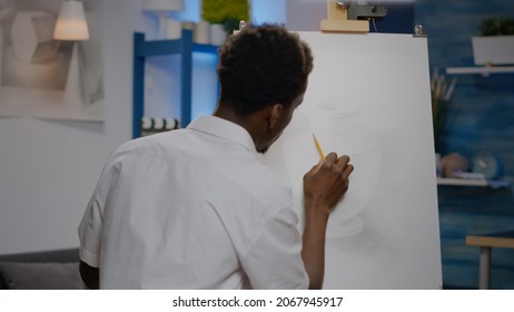 Black Young Artist Retouching Vase Design On Canvas And Easel Using Pencil And Art Tools In Creativity Studio Space. African American Person Drawing Professional Masterpiece For Hobby