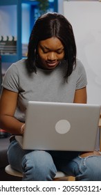 Black Young Artist Typing On Laptop For Art Project While Sitting In Workshop Space At Home. African American Creative Woman Using Device And Technology For Masterpiece And Craft Concept