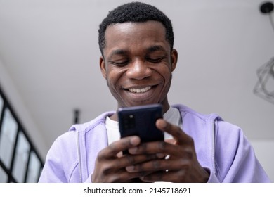 Black young man using smartphone at home pressing finger, reading social media internet, typing text or shopping online Mobile phone in two black hands