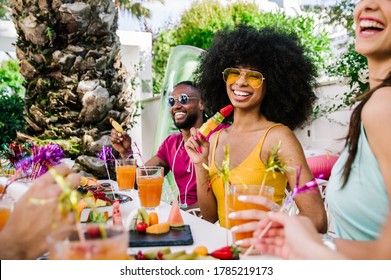 Black Young Woman Smiling At The Camera Celebrating With Friends. Diverse People Hanging Out Toasting And Drinking Cocktails Outdoor.