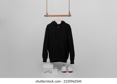 Black Zip Hoodie Hanging On Wood Hanger Isolated On Plain Background