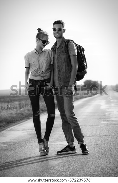 Black-and-white portrait of a\
fashionable models wearing jeans clothes on a highway. Denim style.\
