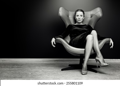 Black-and-white portrait of a stunning fashionable model sitting in a chair in Art Nouveau style. Business, elegant businesswoman. Interior, furniture.