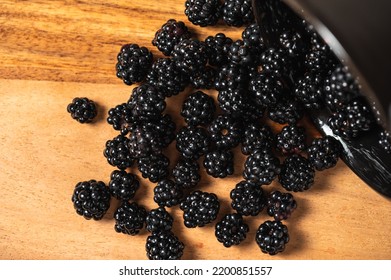 Blackberries Falling From A Bowl Onto A Wooden Board