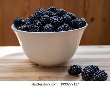 Blackberries in a white bowl on a wooden table