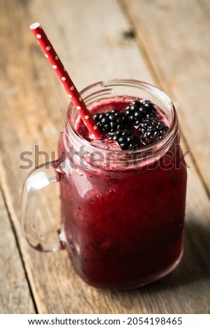 Blackberry cocktail with crushed ice in glass jar on the rustic wooden background. Selective focus. Shallow depth of field.