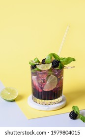 Blackberry Mojito Cocktail With Lime On Modern Yellow Paper Background. Summer Freshness Beverage For Festive Party. Holiday Mocktail With Copy Space.