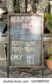 Blackboard Advertising Happy Hour At A Beach Cafe.