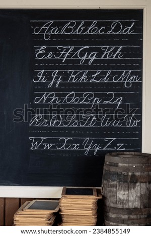 Blackboard with cursive writing and stack of slates