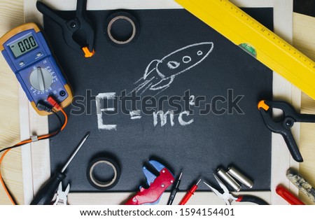 
Blackboard with Einstein's formula and engineering tools.