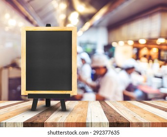 Blackboard Menu With Easel On Wooden Table With Blur Open Kitchen At  Restaurant Background, Copy Space For Adding Your Content