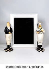 Blackboard With No Signs Empty And Besides Standing Decorative Ceramic Chef Cook And Waiter On The White Background