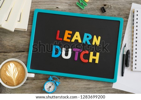 Blackboard on wooden table with Learn Dutch recommendation from plastic letters

