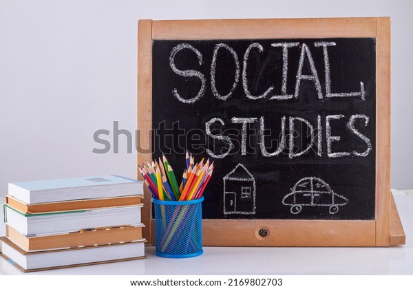 Blackboard with pencil cup and stack of books.\
Social studies\
concept.