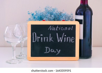 Blackboard with words National Drink Wine Day on the table with a wine bottle and two glasses. - Powered by Shutterstock