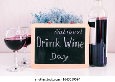 Blackboard with words National Drink Wine Day on the table with wine bottle and two glasses with red wine. - Powered by Shutterstock