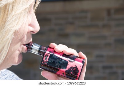 Blackburn, Lancashire/UK - May 16th 2019: Close Up Of Middle Age Blonde Hair Caucasian Woman Smoking An Electronic Cigarette Outdoors