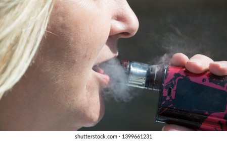 Blackburn, Lancashire/UK - May 16th 2019: Close Up Of Middle Age Blonde Hair Caucasian Woman Smoking An Electronic Cigarette Outdoors