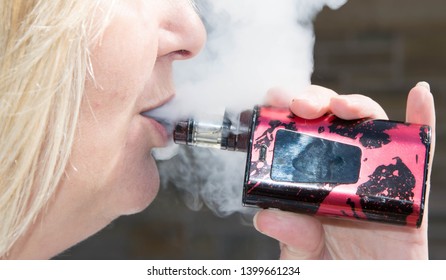 Blackburn, Lancashire/UK - May 16th 2019: Close Up Of Middle Age Blonde Hair Caucasian Woman Smoking An Electronic Cigarette Outdoors