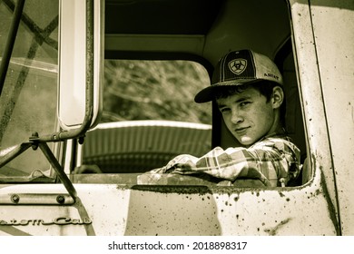 Blackfork, Arkansas, USA- September 1, 2020- A Young Teenage Boy Sitting In The Drivers Seat Of A Large Antique Farm Truck, Wearing A Ariat Hat