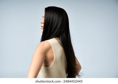 Black-haired woman in sleeveless top smiles over shoulder. - Powered by Shutterstock