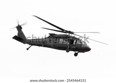 Blackhawk helicopter operated the United States Army. Government aircraft in all black flying by isolated on white background. Military airborne transport flown by National Guard