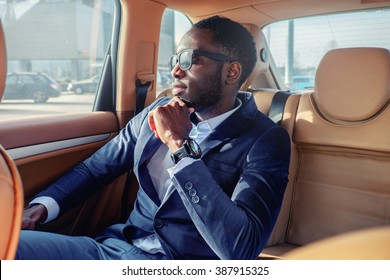 Blackman in a suit in the car.