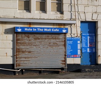 Blackpool, Lancashire, United Kingdom - 4 March 2022: Hole In The Wall Cafe On The Seafront In Blackpool With Closed Shutter And Menu Board