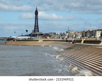 Blackpool, Lancashire, United Kingdom - 5 March 2022: Scenic View Of Blackpool From The South With Waves Breaking On The Steps, People On The Promenade And The Golden Mile And Tower In The Distance