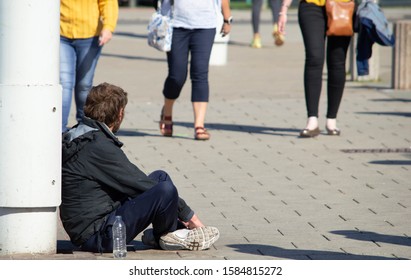 Blackpool, Lancashire/UK - September 21st 2019: Homeless Unemployed Caucasian Man Sat On Pavement With People Walking By