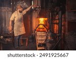 Blacksmith in an authentic forge fans the fire with hand-held bellows. Traditional crafts