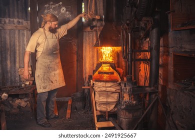 Blacksmith in an authentic forge fans the fire with hand-held bellows. Traditional crafts