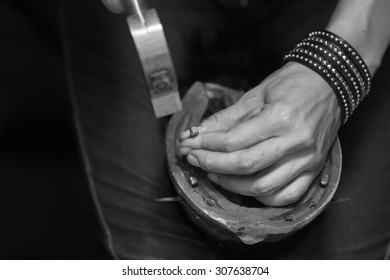 Blacksmith, or equine farrier, nails a horse shoe to a horse's hoof, close up - Powered by Shutterstock