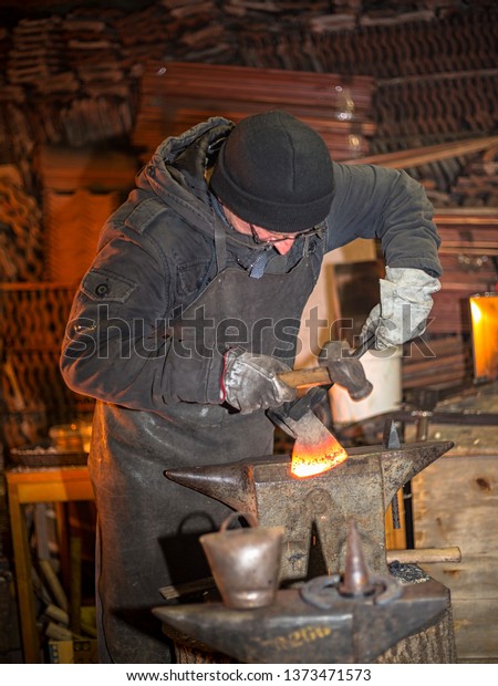 A blacksmith forges an\
ax on fire 