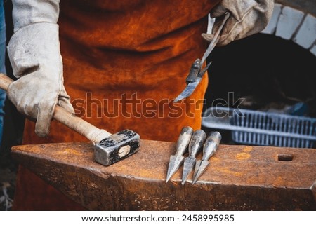 A blacksmith forges iron. Blacksmith's workshop. Blacksmith's anvil and hammer.