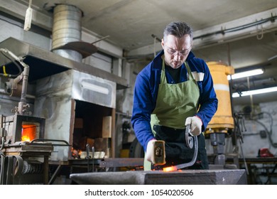 The blacksmith forges the luminous metal in the furnace, kicks out the sparks - Powered by Shutterstock