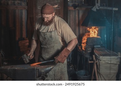 Blacksmith forges a red-hot metal piece on an anvil in a rural forge. Traditional crafts - Powered by Shutterstock