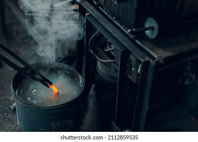 Blacksmith forges and tempering metal horseshoe in jar with water at forge. - Shutterstock ID 2112859535