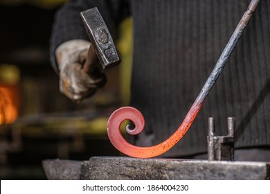 A Blacksmith Forging A Curl From A Red-hot Flattened Billet With A Hammer. Handmade In The Forge Concept