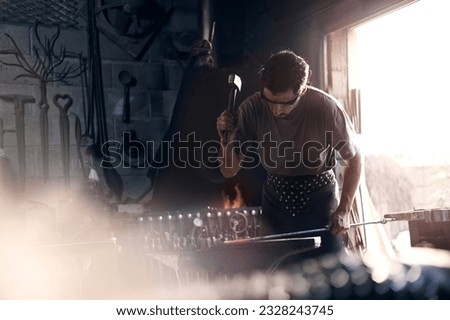 Blacksmith forging iron at anvil in forge