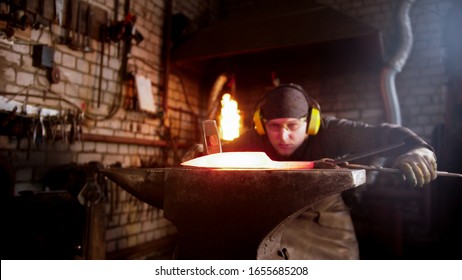 Blacksmith Forging A Knife Blade In Workshop Using A Hammer