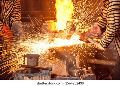 Blacksmith forging the molten metal with a hammer to make keris in the blacksmith's workshop - Shutterstock ID 1564252438